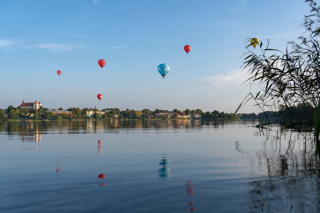 A group of hot air balloons ballooning over a body of water.