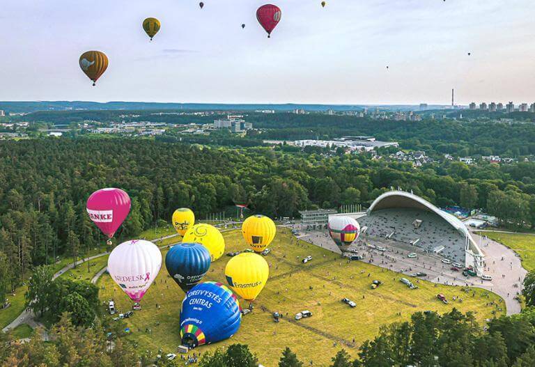 Hot air balloons soaring above a lush forest.