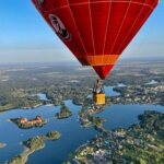 A Dovanų kuponai skrydžiui oro balionu - VIP privatus skrydis dviems asmenims soaring over a serene lake.