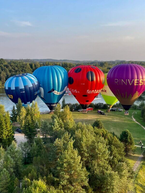 A group of colorful hot air balloons floating over a river.